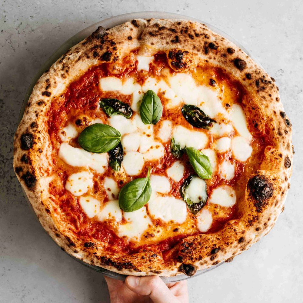 pizza met tomatensaus, kaas, olijven en een paar basilicumblaadjes